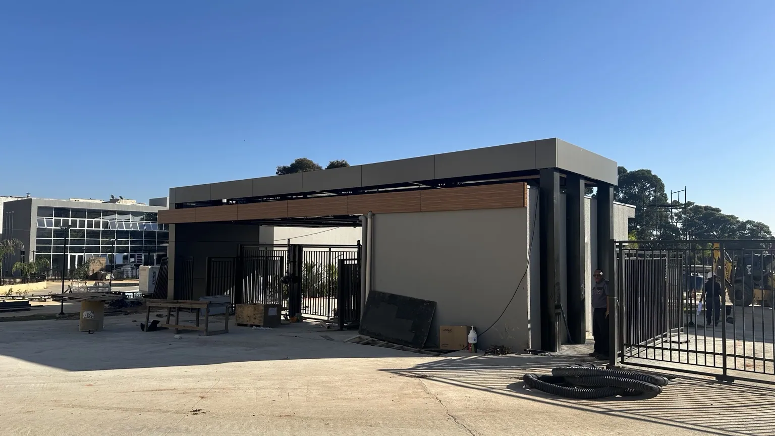 Pórtico e cobertura de acesso com revestimento grafite e detalhes amadeirados