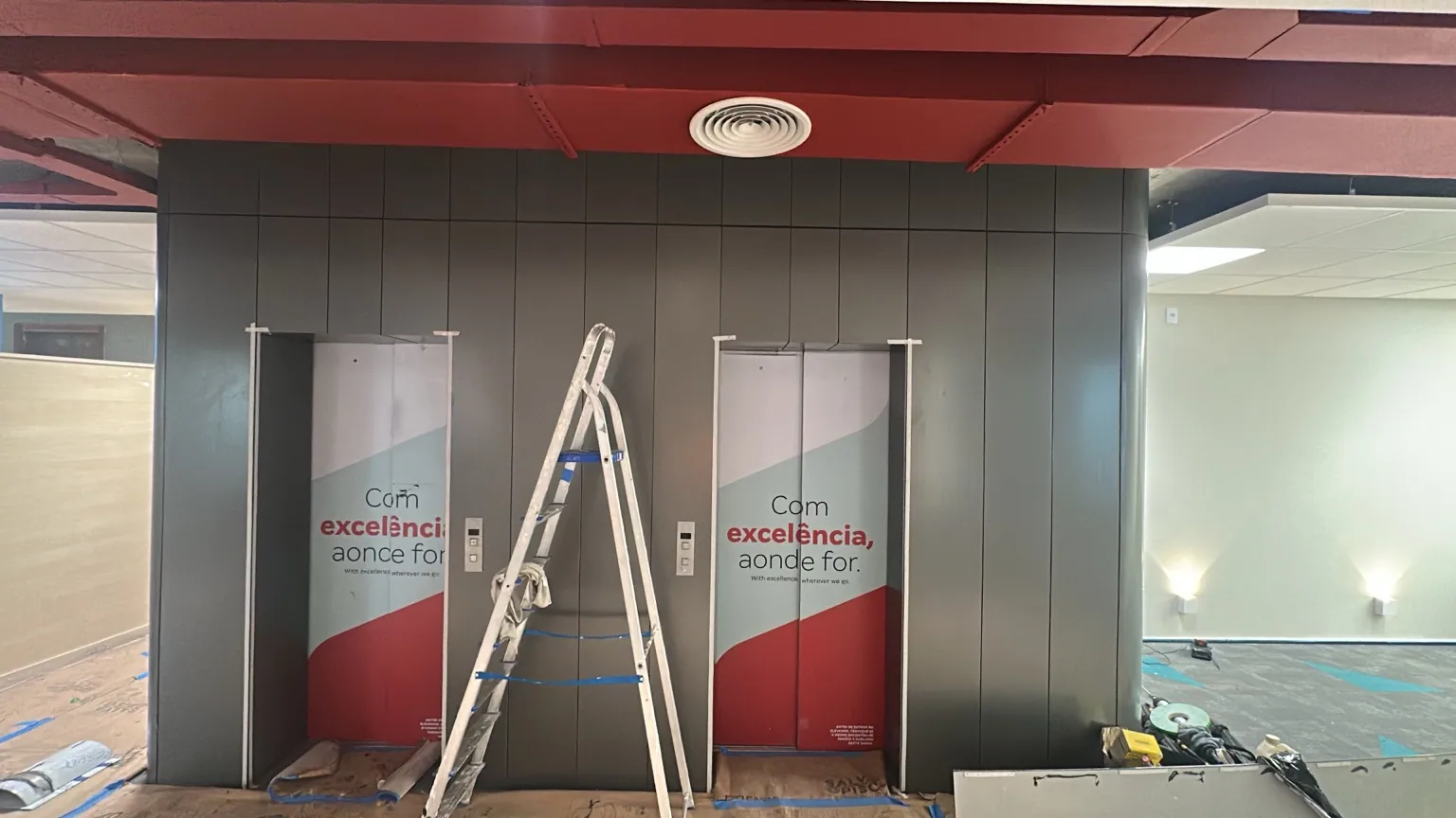 Painéis de revestimento cinza instalados junto a elevadores em ambiente corporativo