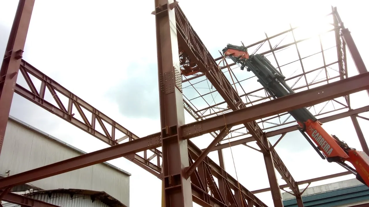 Estrutura metálica industrial em montagem com equipamento de içamento