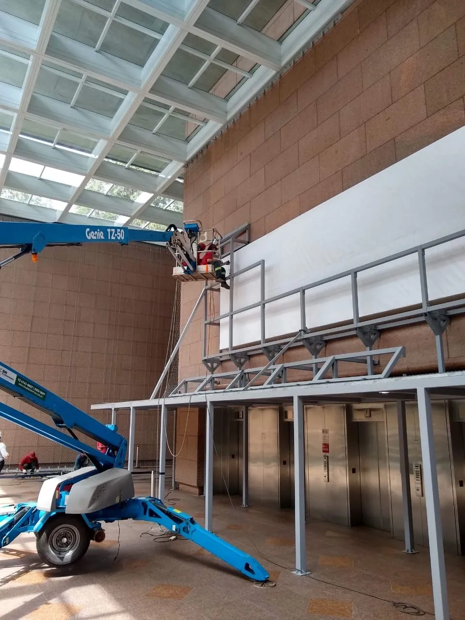 Estrutura metálica elevada instalada em frente a elevadores em grande hall