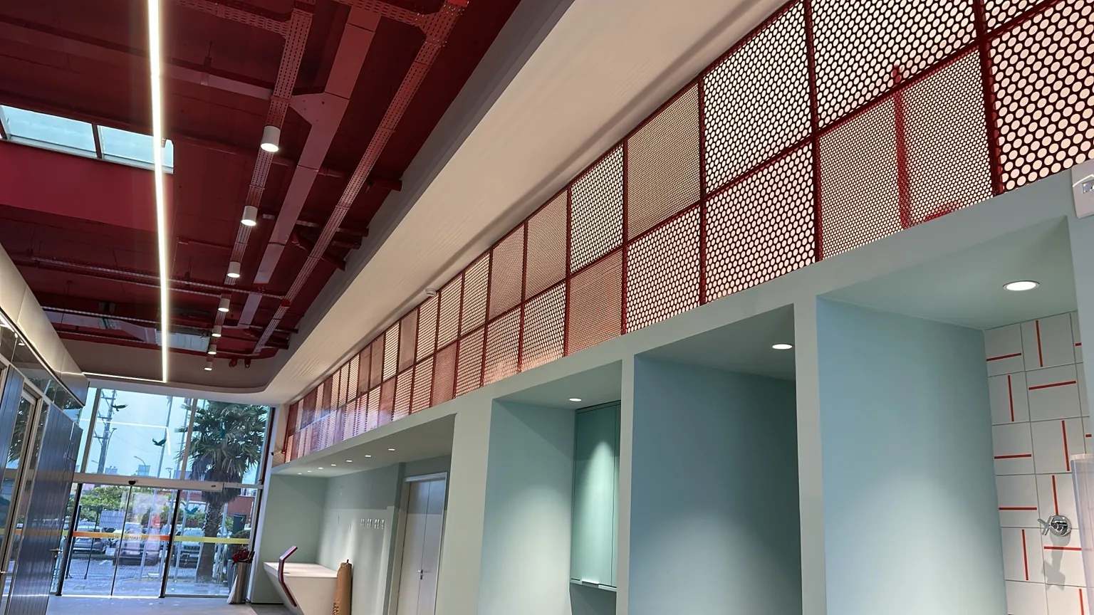 Painel perfurado metálico vermelho instalado acima de circulação interior